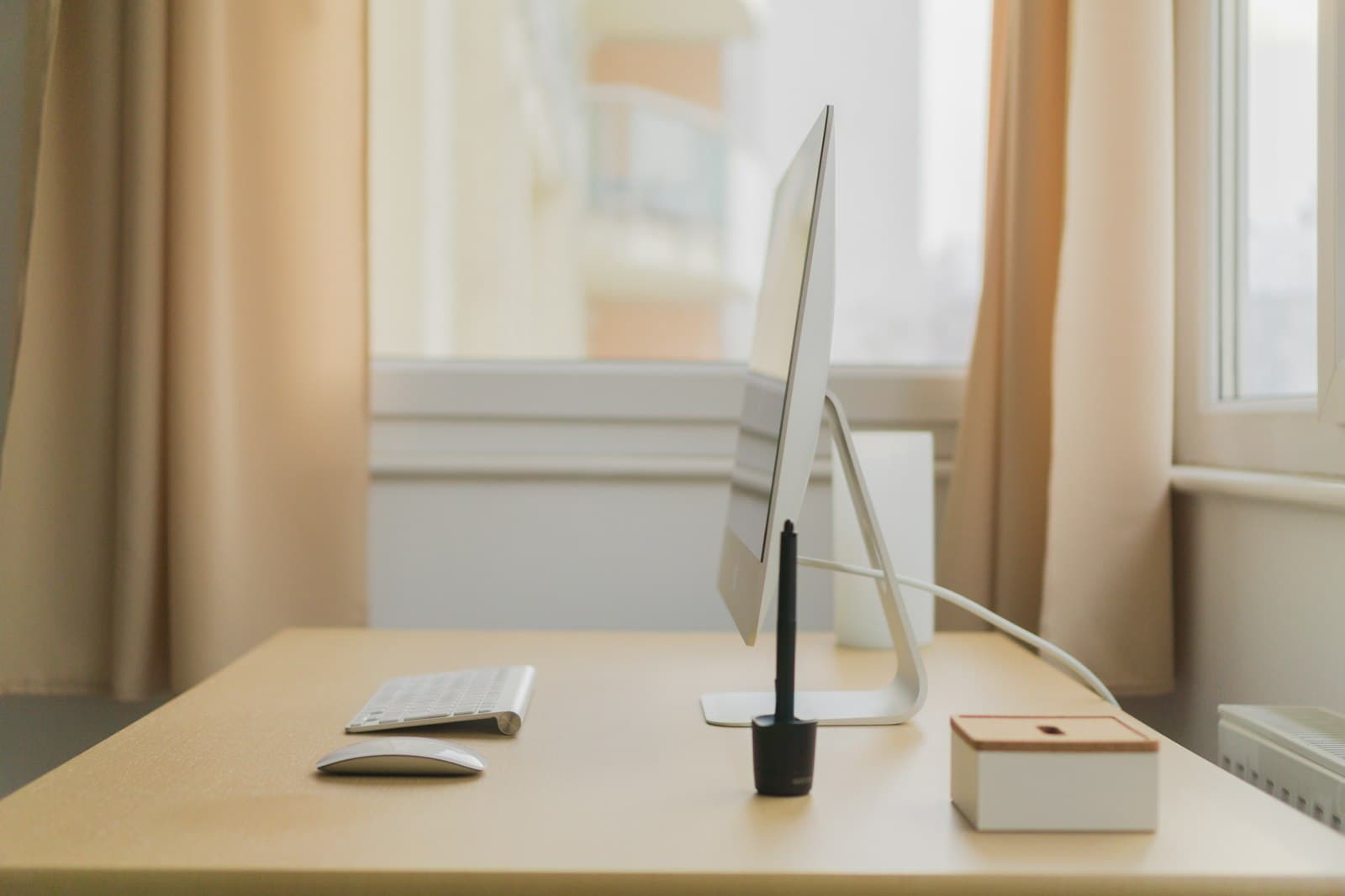 Bureau en bois chaud sous une lumière douce de fenêtre, avec clavier et souris et un seul câble bien rangé
