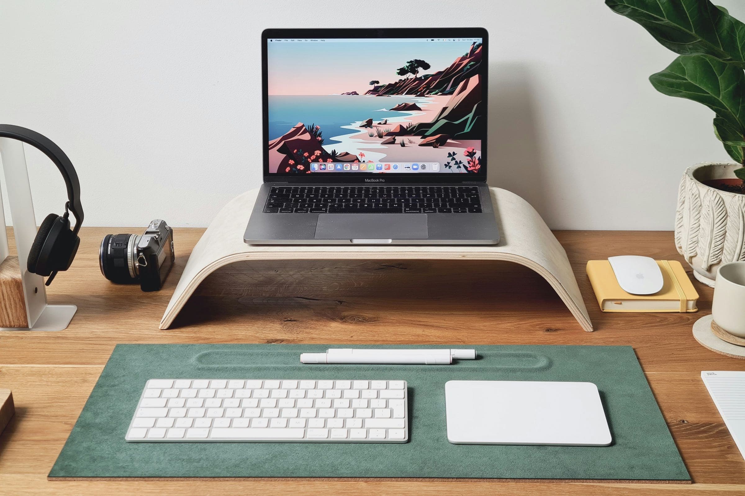 Poste de télétravail calme avec un ordinateur portable surélevé et un clavier séparé, près d'une fenêtre